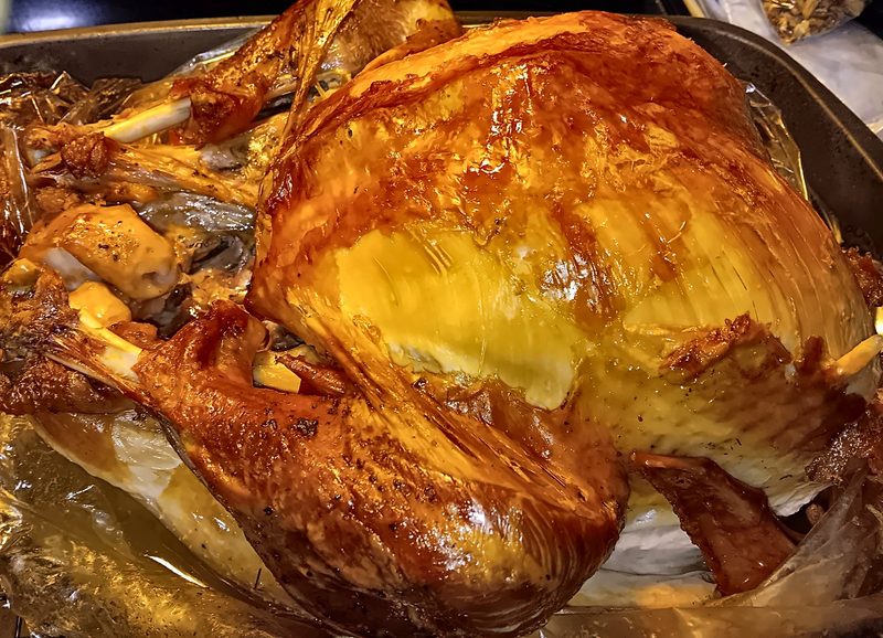 A whole roast turkey with glistening golden skin in a roasting pan